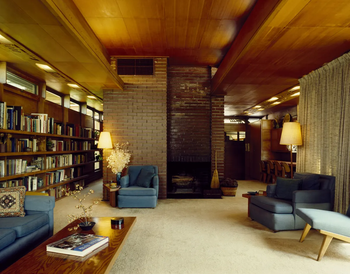 Warm mid-century living room with a brick fireplace and bookshelves, a home type covered in our property management FAQ