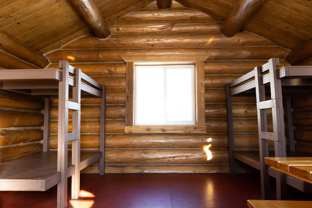 Log cabin interior with bunk beds and a sunny window, a guest-ready rental space for hosts who list a Central Oregon rental